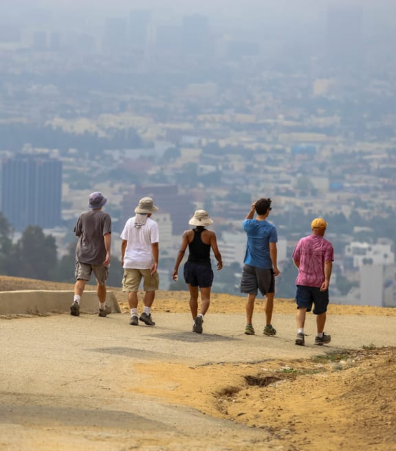 a group of people walking down a dirt road overlooking a city