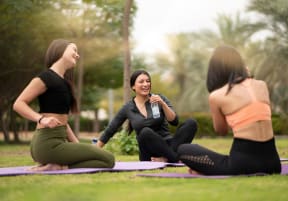 a group of women sitting on a yoga mat in a park at York House, Saint Louis, MO, 63108