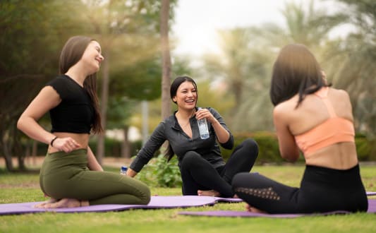 a group of women sitting on a yoga mat in a park at 2200 LaSalle, St Louis