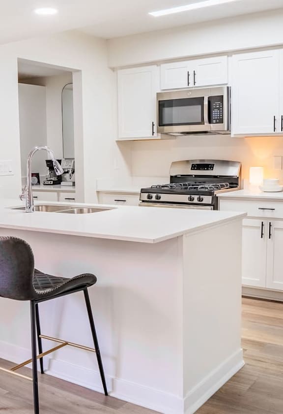 A kitchen with a white countertop and a fridge.