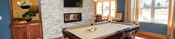 a pool table in a living room with a fireplace and a tv