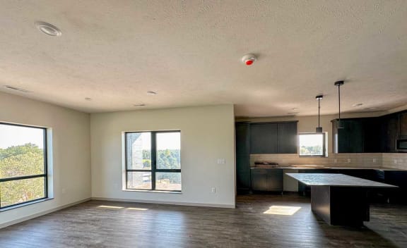 an empty room with a kitchen with dark brown cabinets and island