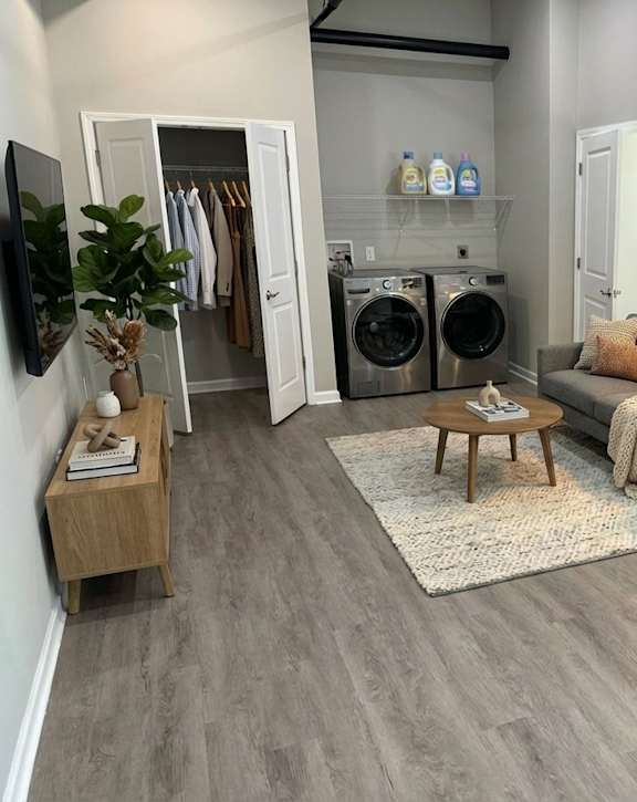 A modern laundry room with a washer and dryer, a refrigerator, and a small wooden table.