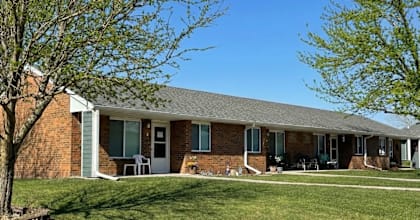 A house with a green lawn and a tree in front.
