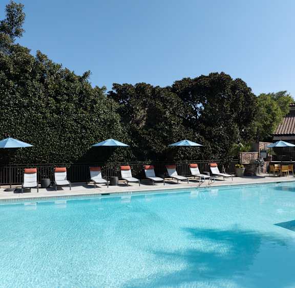 a swimming pool with chairs and umbrellas at a resort
