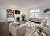 Thumbnail 4 of 11 - A living room with a fireplace, a white sofa, and a coffee table at Queen St East in Scarborough, ON