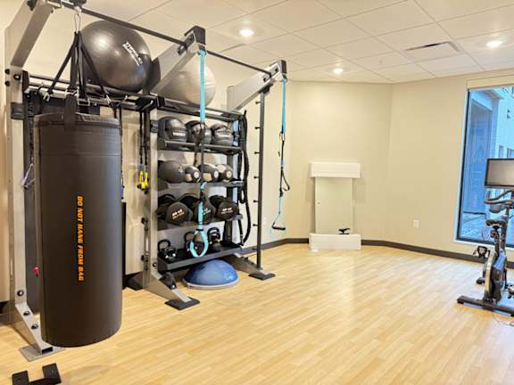 a fitness room with a punching bag and weights on a rack