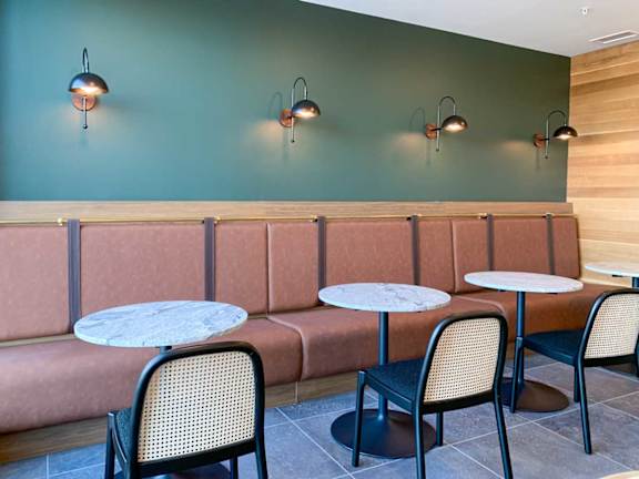 a row of chairs and tables and booth seating in front of a modern green wall