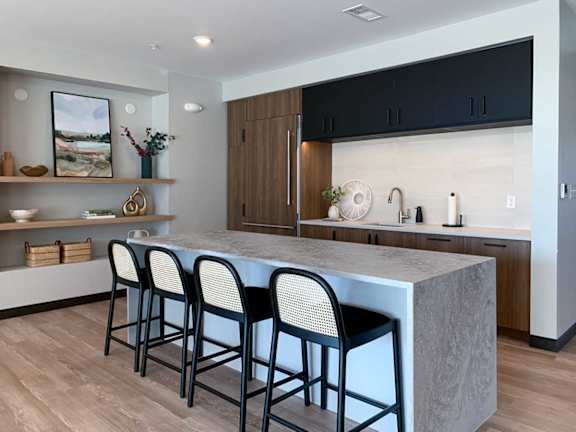 A kitchen with a marble countertop and black barstools.