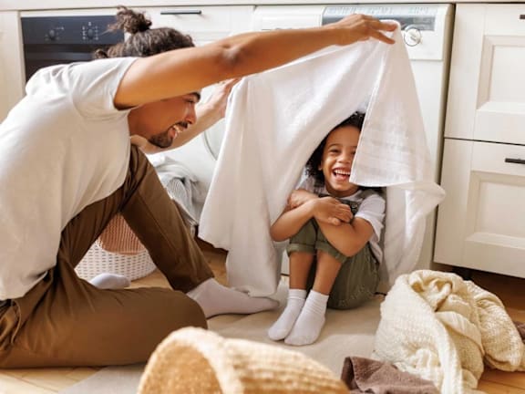 a mother and father playing with their child under a towel
