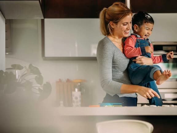 a woman holding a child in a kitchen