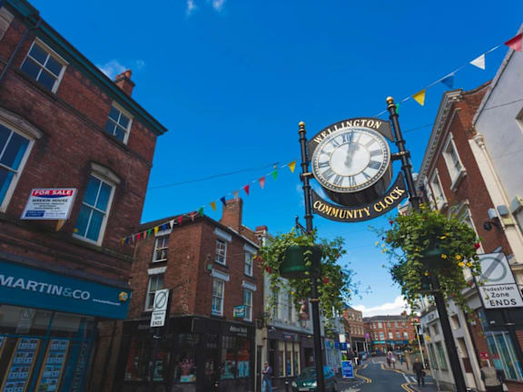 a clock on the side of a building on a street