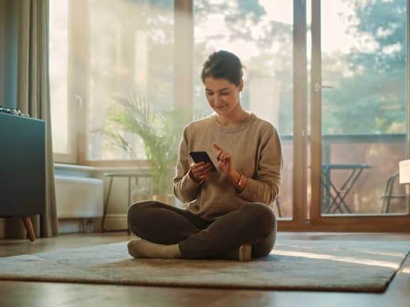 a woman sitting on the floor looking at her cell phone
