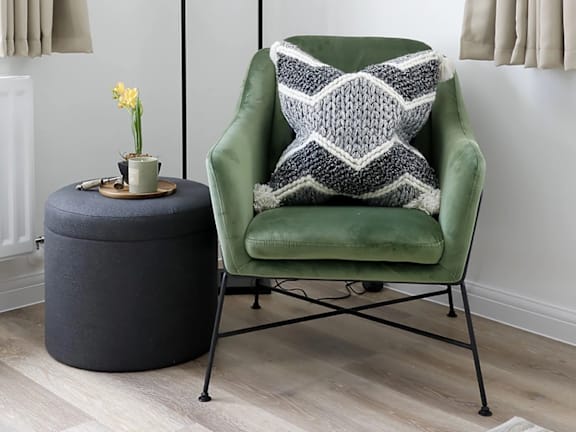 a green chair with a blanket and a round table next to it