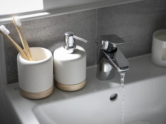 a bathroom sink with two toothbrushes and a water faucet