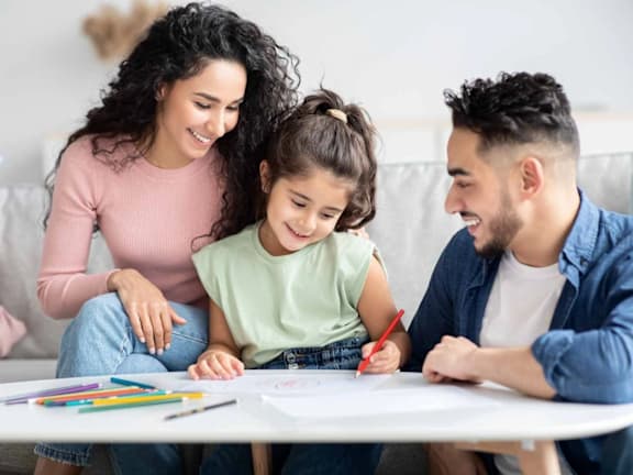 a young girl sitting at a table with her family