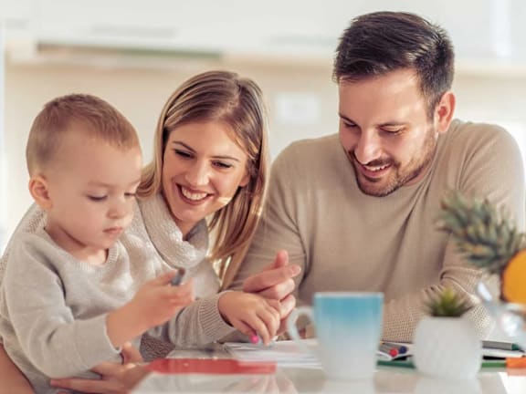 a young family sitting at a table playing with a child