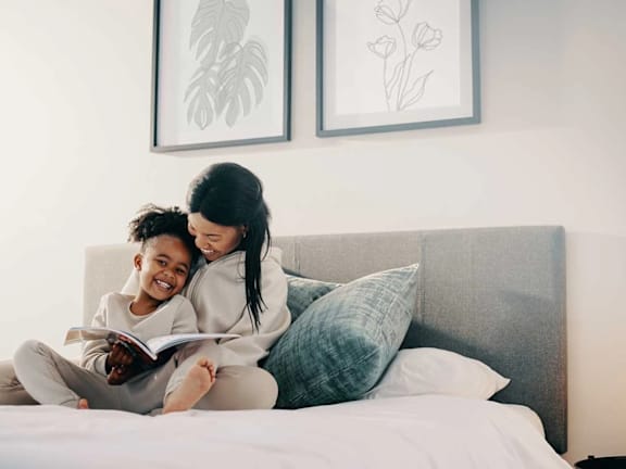 a woman and a child reading a book on a bed