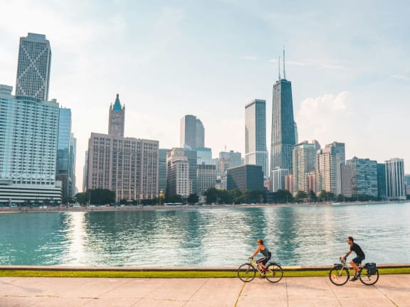 two people riding bikes with the skyline in the background