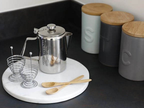 a tray with a coffee maker and utensils on a table