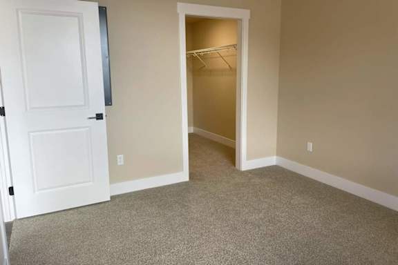 A room with a white door and a carpeted floor.
