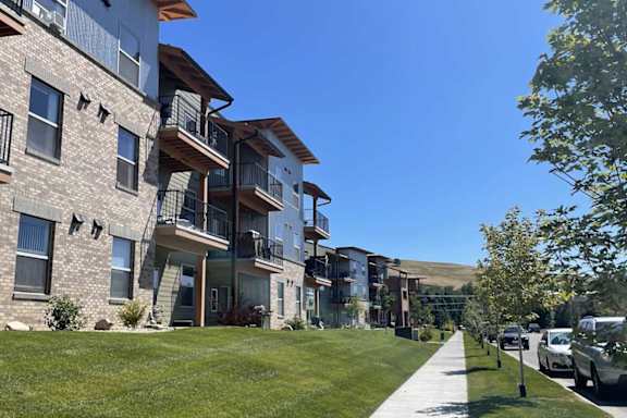 A row of apartment buildings with a sidewalk in front.