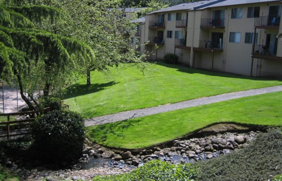 the view of an apartment complex with a green lawn and sidewalk