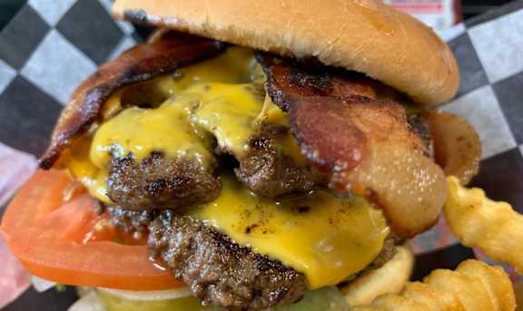 A burger with cheese, bacon, and fries.
