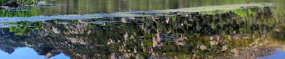 A mountain range is reflected in the still water of a lake.