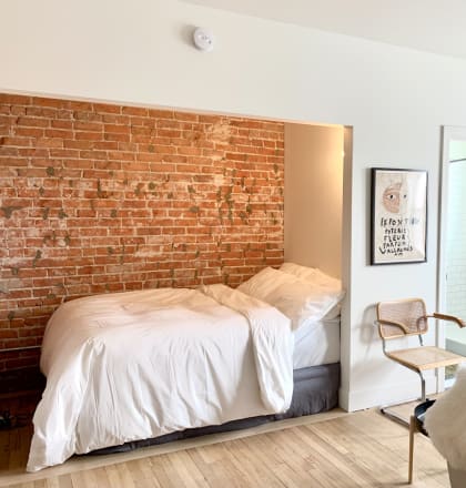 a brick wall in a bedroom with a bed and a couch