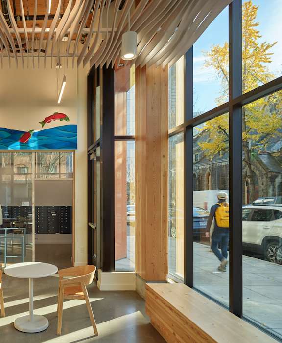 A modern cafe with wooden tables and chairs and a glass wall.