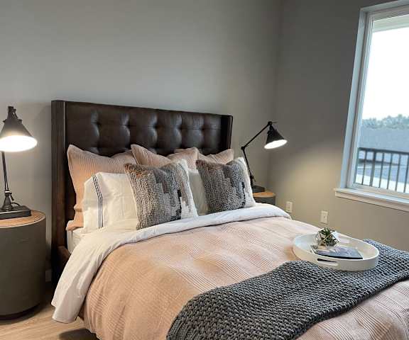 A bedroom with a queen-size bed, a dresser, decorations, window, and nightstands at LIVEasy Apartments. 