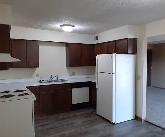 A white refrigerator stands in a kitchen with brown cabinets.