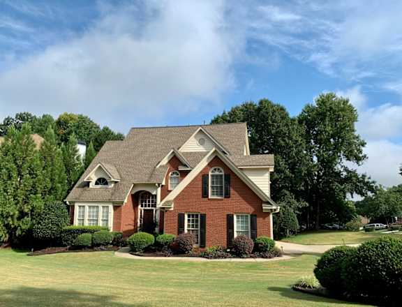 A house with a red brick exterior and a well-manicured lawn.