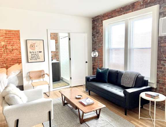 a living room with a couch and a coffee table and a brick wall