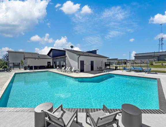 A swimming pool surrounded by lounge chairs and a building in the background.