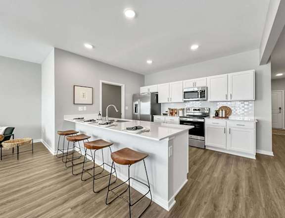 A modern kitchen with white cabinets and a long island.