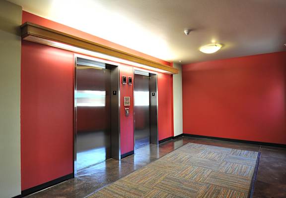 Two elevators in a hallway with red walls.