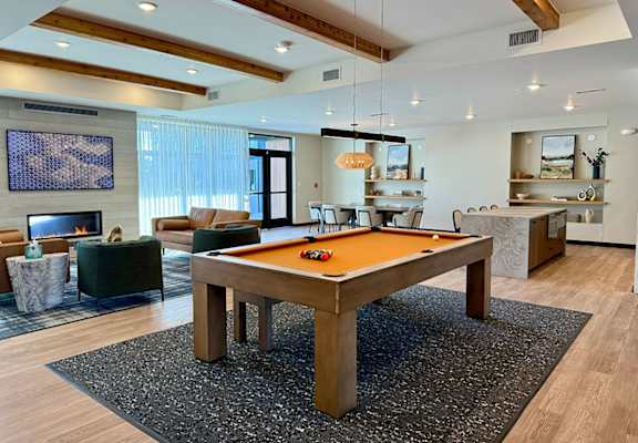 A pool table in the middle of a room with a fireplace and a TV