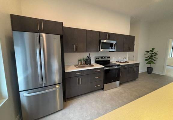 A modern kitchen with a stainless steel refrigerator and dark brown cabinets. at The Annex Apartments, Buffalo, NY, 14222