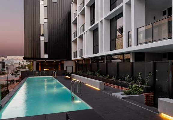 a swimming pool at night in front of an apartment building