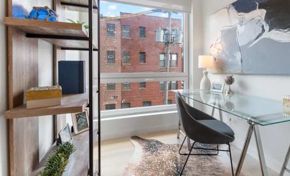 a home office with a large window and a desk with a chair