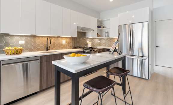 a kitchen with stainless steel appliances and a counter with two stools