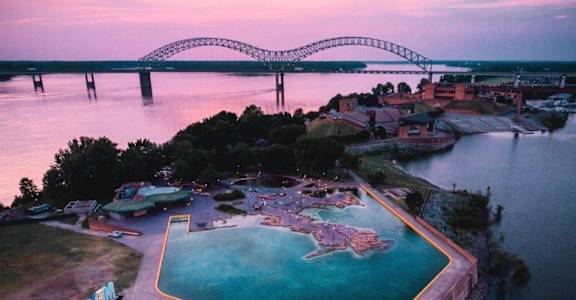 A bridge spans across a body of water with a pool in the foreground.