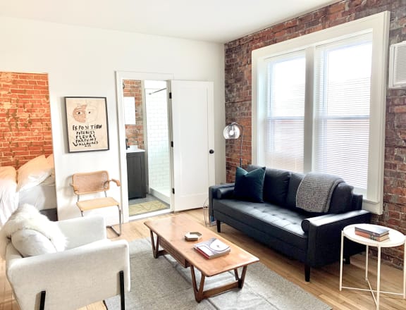 a living room with a couch and a coffee table and a brick wall