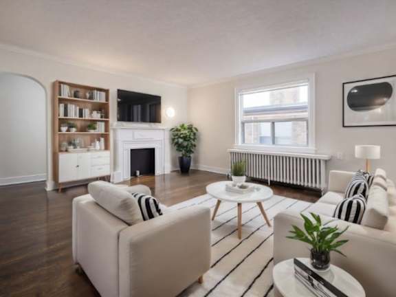 A living room with a fireplace, a white sofa, and a coffee table at Queen St East in Scarborough, ON