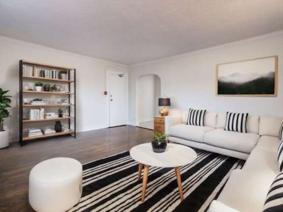 A living room with a white couch, a black and white striped rug, and a wooden coffee table at Queen St East in Scarborough, ON