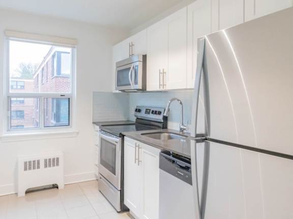 A white kitchen with a black fridge and stove at Queen St East in Scarborough, ON