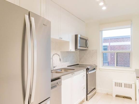 A white kitchen with a refrigerator, microwave, oven, and sink at Queen St East in Scarborough, ON