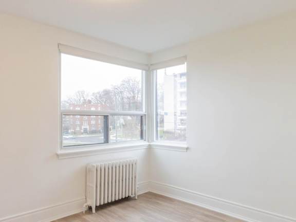 A white room with a window and a radiator on the floor at Queen St East in Scarborough, ON